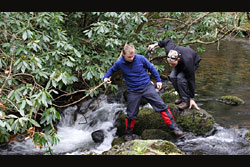 Chris and James S. climbing on rocks in the river