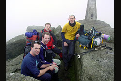 Four boys sitting on rocks in the mist