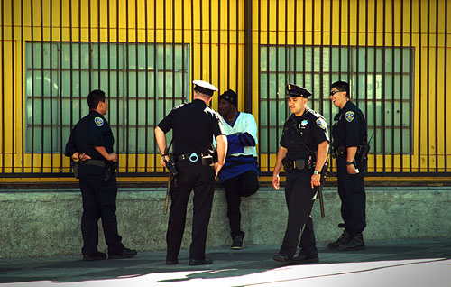 Four policemen talking to a black man at 16th and Mission BART station