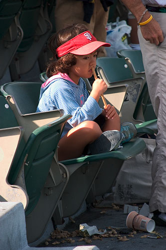 A bored little girl sitting at a baseball game