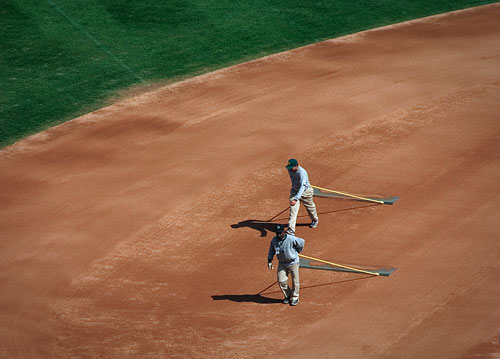 Two guys sweeping the infield at the Oakland A’s stadium