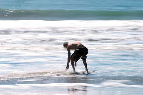 man skim-surfing in the sea