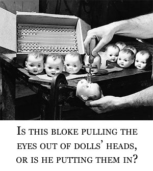 A man with some dolls' heads, a bunch of dolls' eyes and a funny tool